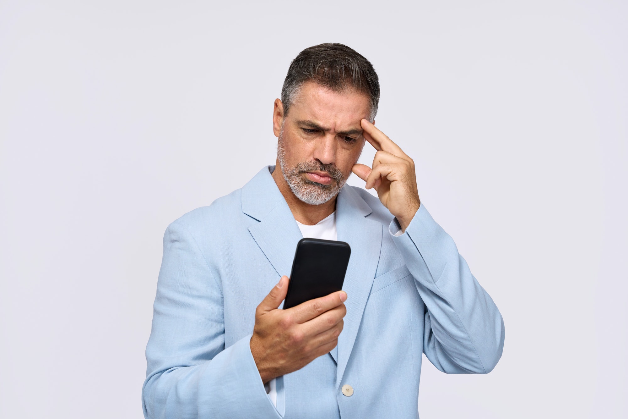 Confused middle aged business man looking at smartphone isolated on white.